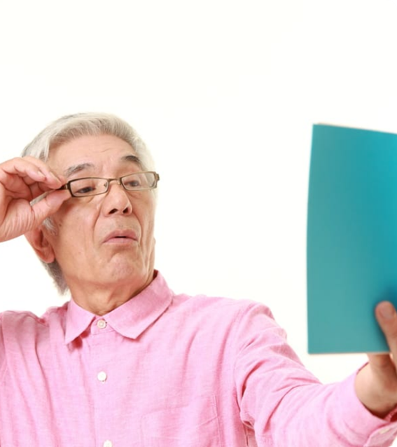Persona de mediana edad leyendo un libro alejándolo para enfocar